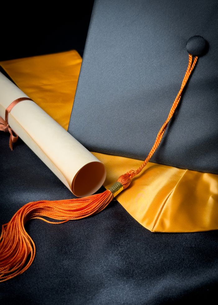 Graduation cap and diploma on a yellow sash, symbolizing academic achievement.